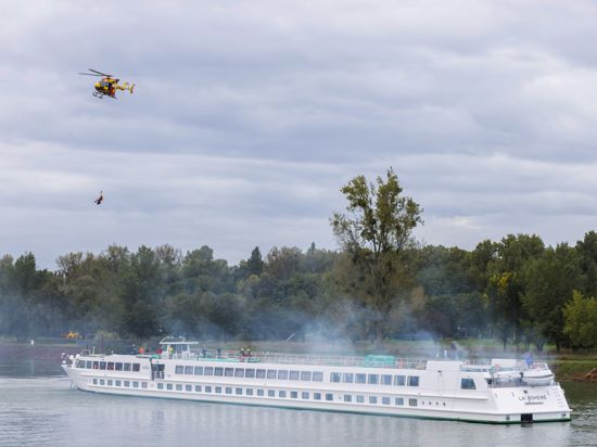 Ein Helikopter der französischen Sécurite Civile schwebt während einer binationalen Übung über einem Passagierschiff bei Kehl und seilt einen Helfer ab.
