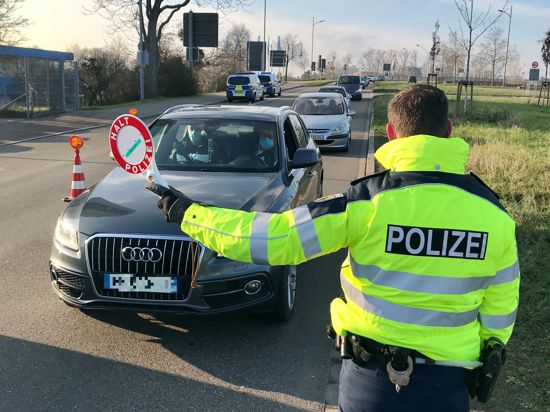 Ein Bundespolizist bringt am Kehler Grenzübergang an der Europabrücke ein Auto mit einer Warnkelle zum Stehen.