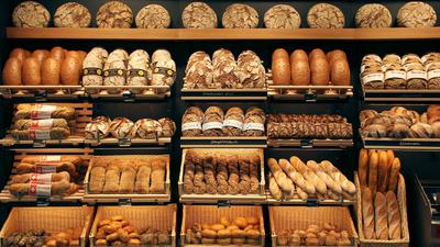 Brote verschiedenster Sorten liegen in Körben und auf Regalen.