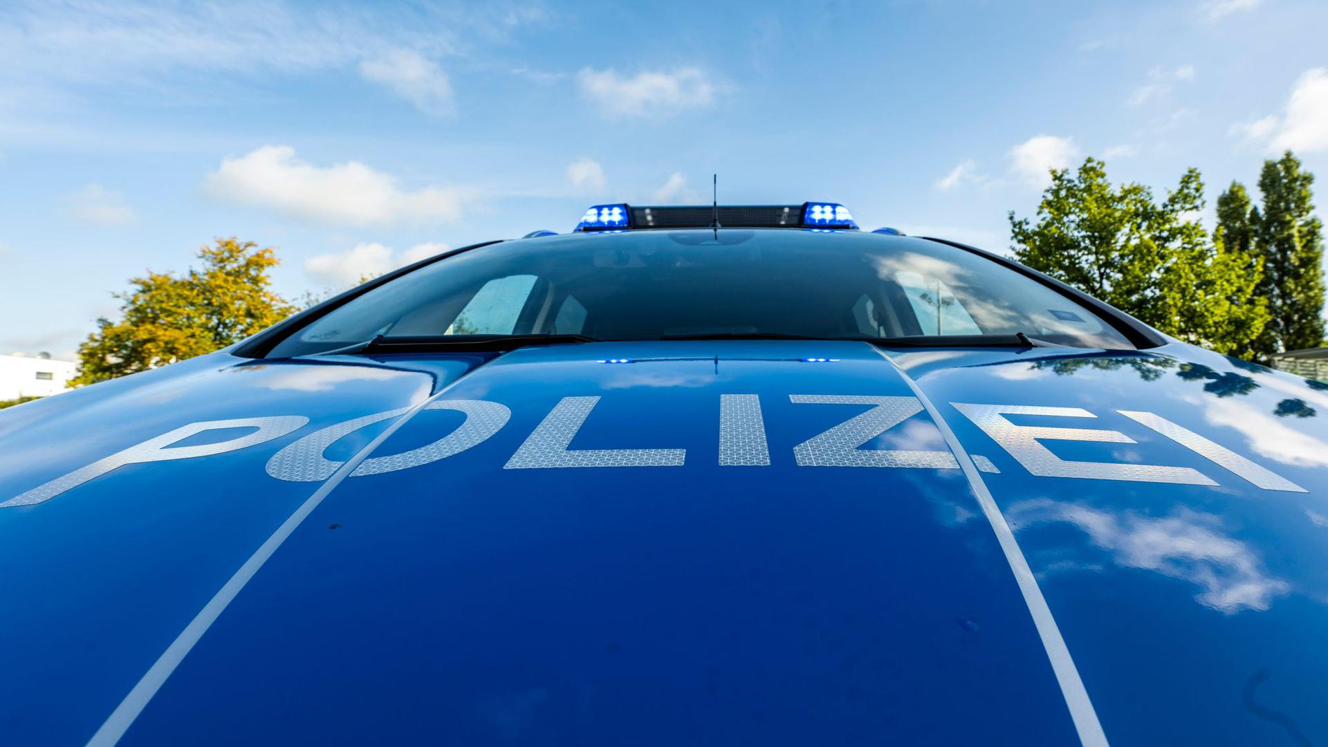 Auf der Motorhaube eines Streifenwagens steht der Schriftzug „Polizei“.