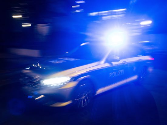 Ein Polizeifahrzeug fährt mit Blaulicht an einem Gebäude vorbei.