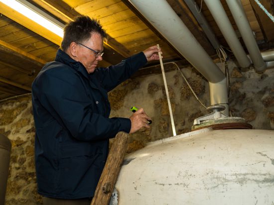 Zollamtsinspekteur Jan Frank misst mit einem Zollstock den Inhalt der Maischefässer im Keller des Oberkircher Schnapsbrenners Josef Brandstetter.