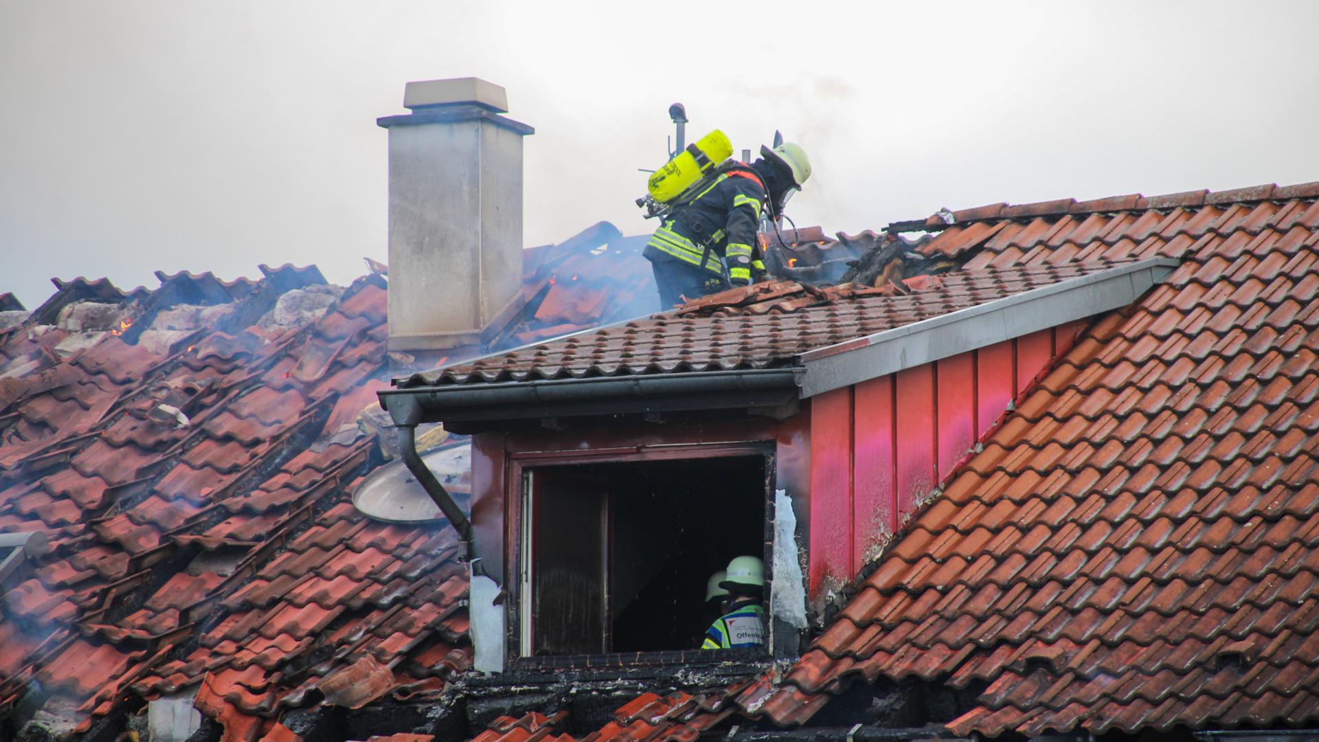 Feuerwehrleute bei Löscharbeiten an einem brennenden Dachstuhl.