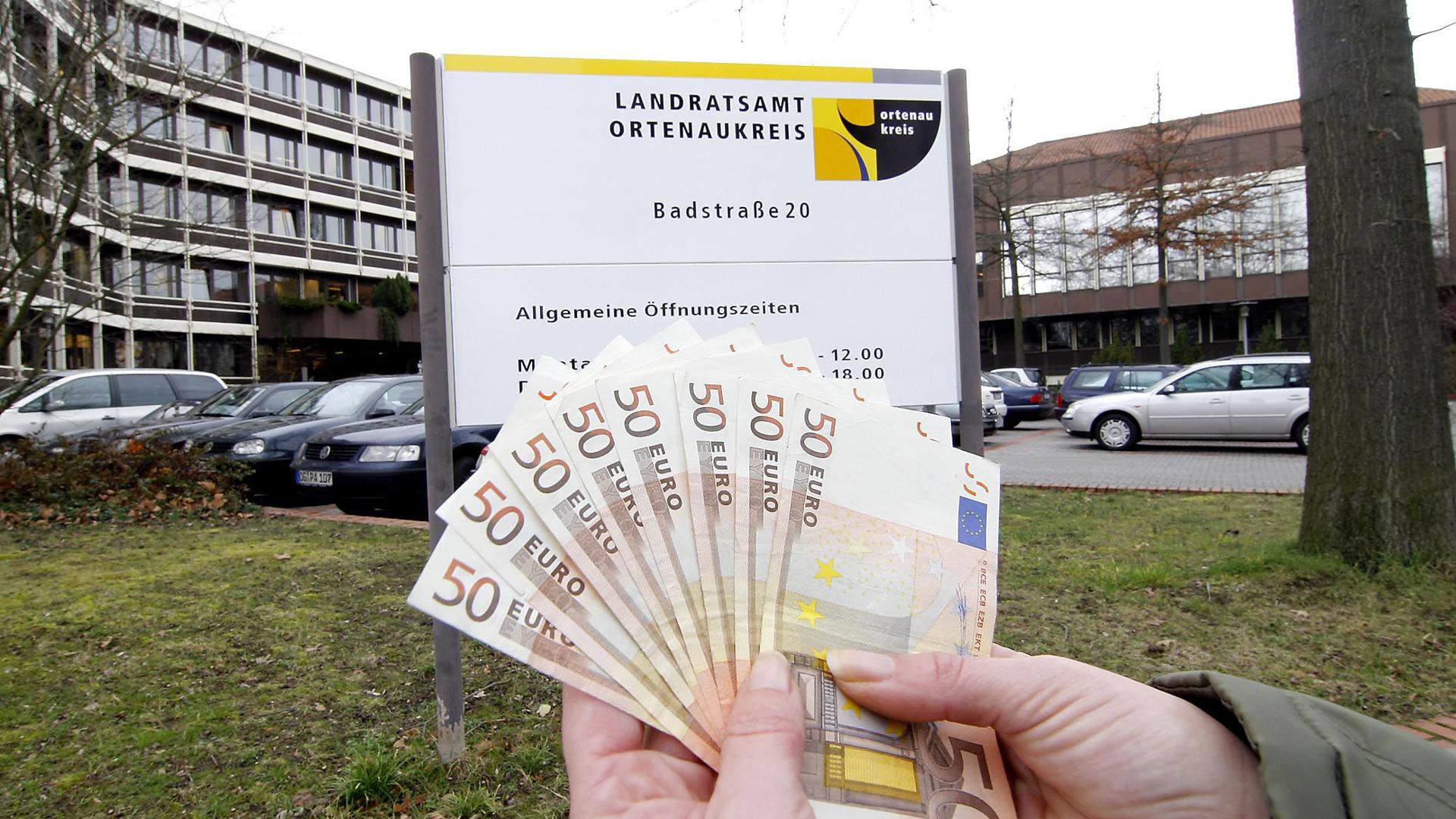 Jemand hält vor dem Offenburger Landratsamt ein Bündel 50-Euro-Noten in der Hand