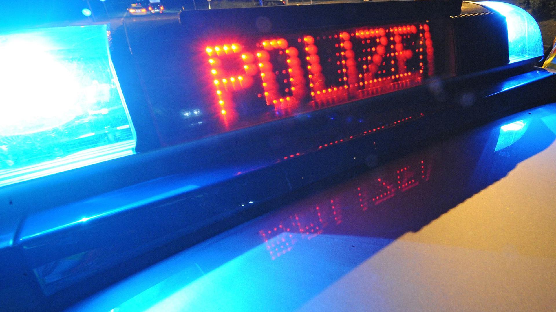 Die Aufschrift „Polizei“ leuchtet auf einem Polizeifahrzeug.