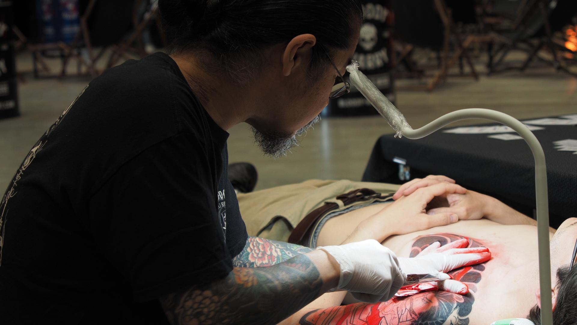 Tätowierer Ryugendo aus Japan sticht die rote Farbe mit Nadeln per Hand statt mit einer elektrischen Maschine unter die Haut.