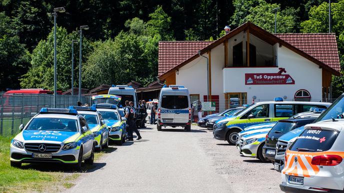 Polizei- und Rettungsfahrzeuge stehen auf einem Sammelplatz nahe der Gemeinde vor einem Sportlerheim.