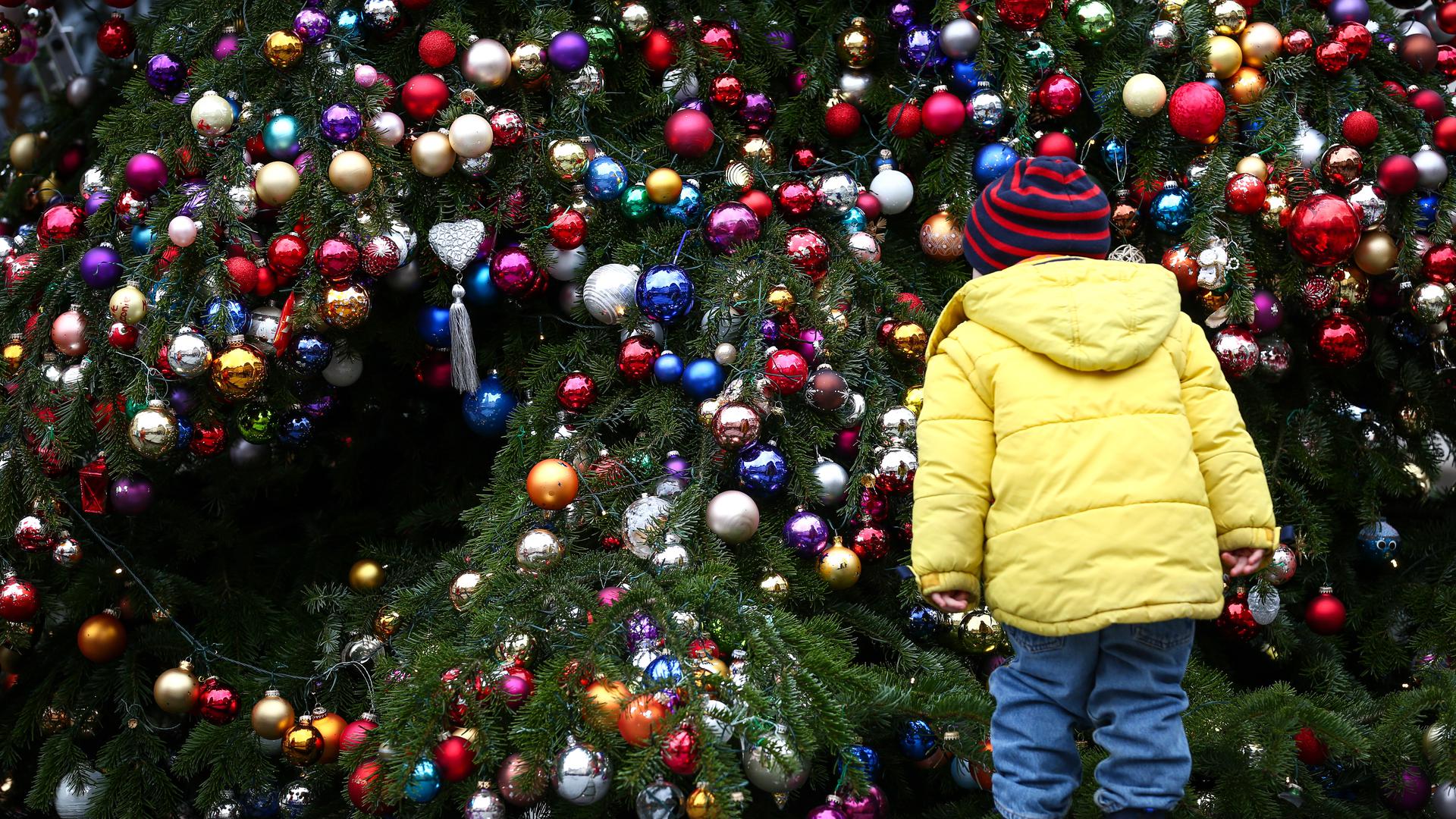 Ein Kind betrachtet am 21.12.2014 am Gabelmann in Bamberg (Bayern) einen mit Christbaumkugeln behangenen Weihnachtsbaum. Der Schmuck wird während der Adventszeit für einen guten Zweck verkauft. Foto: David Ebener/dpa ++
