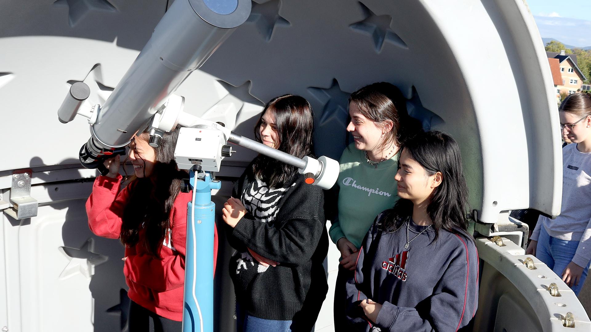 Die Lenderschüler betrachten die Sonnenfinsternis, Bild der Schüler am Teleskop und kurzer Text. 