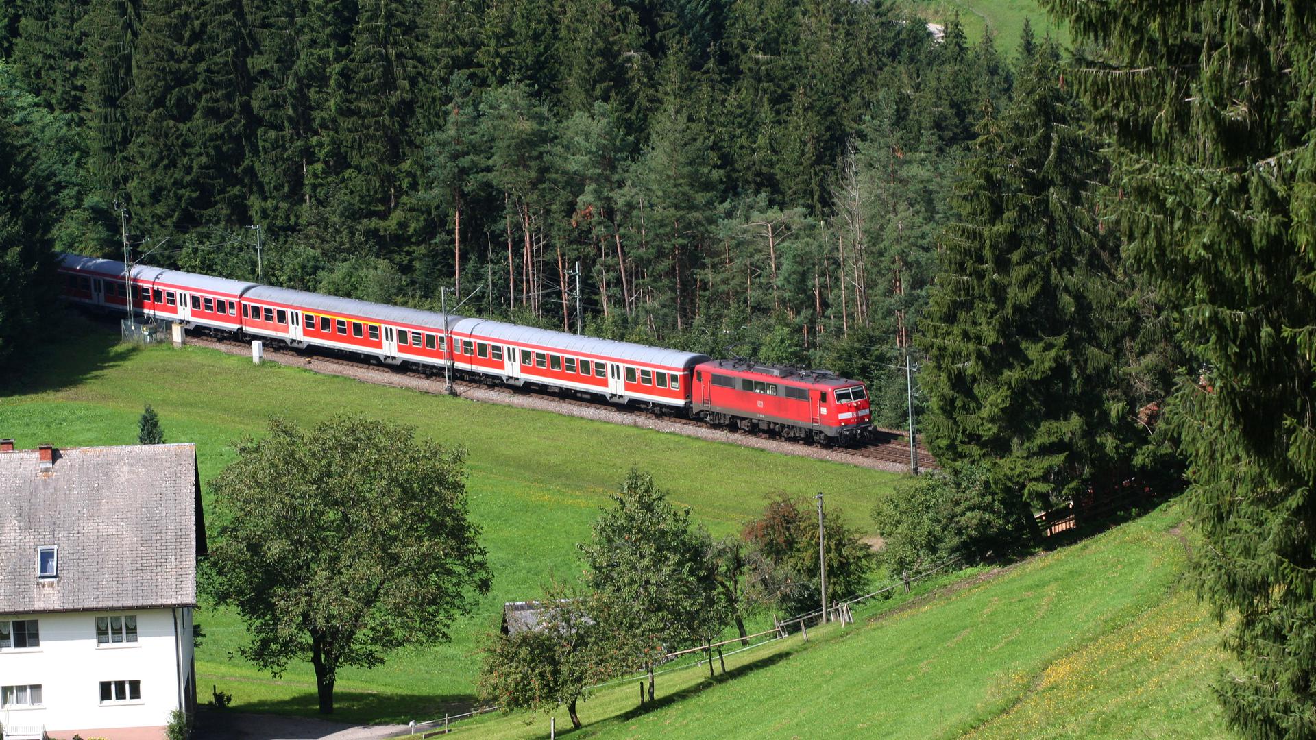 Eine E-Lok der Baureihe 111 mit den klassischen Nahverkehrs-Wagen passiert auf der Schwarzwaldbahn den Unterhippensbachhof. 