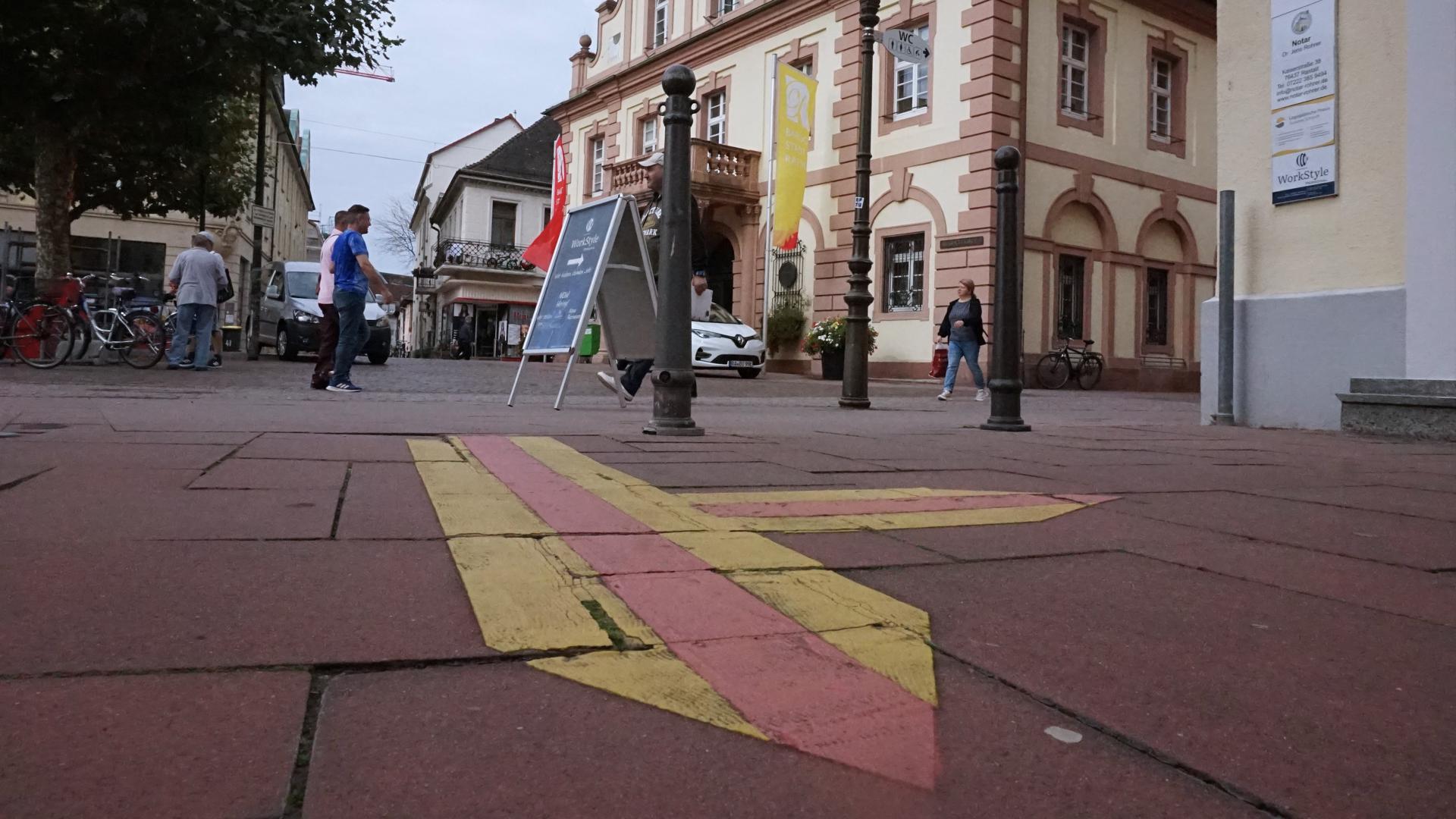 Gelb-rote Pfeilmarkierung auf dem Pflaster vor Rastatter Rathaus