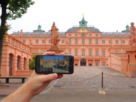Vor dem Rastatter Schloss hält jemand ein iPhone mit dem Karten-Service „Look Around“, der das Schloss zeigt.