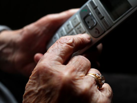 Eine ältere Person hält in ihrer Hand ein Handy.