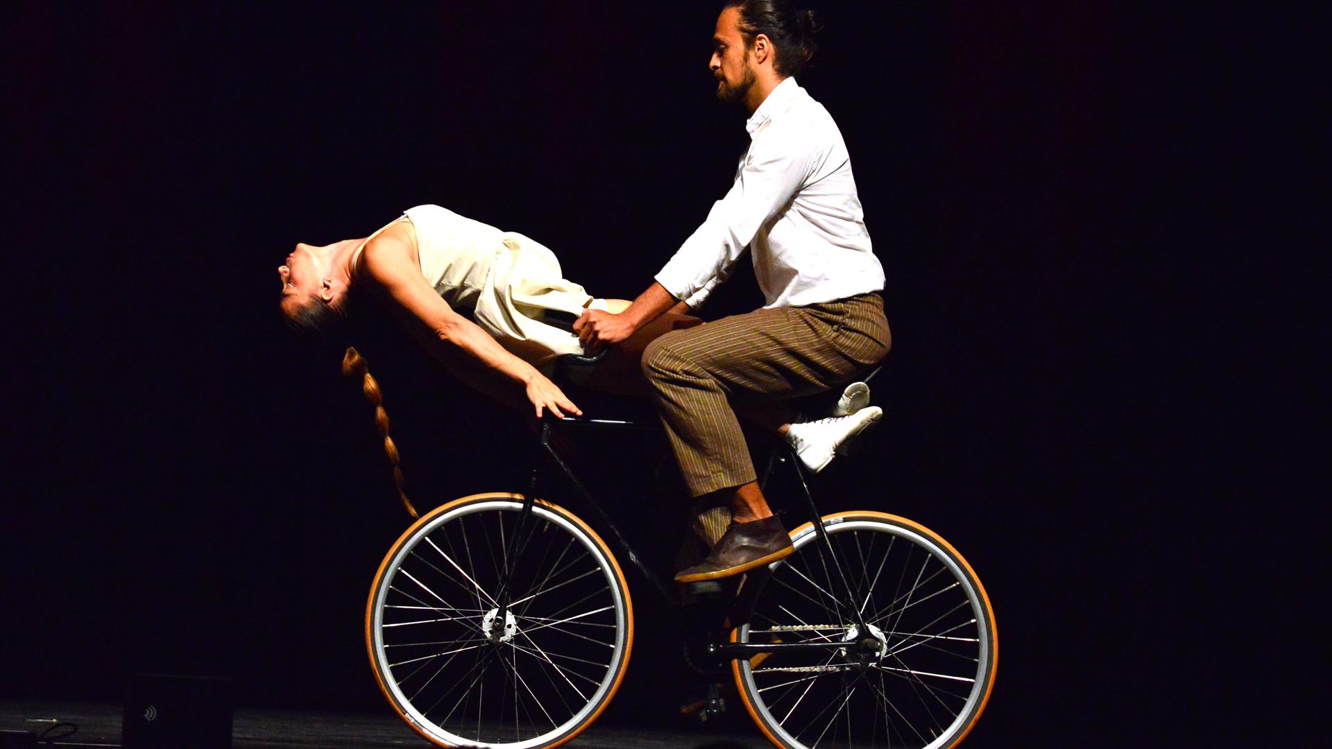 Frau und Mann bei Akrobatik auf einem Fahrrad. 