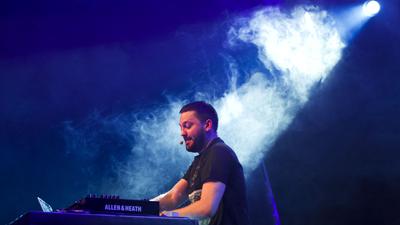 Der Sänger und DJ Fritz Kalkbrenner steht mit seinem Mischpult und Headset auf der Bühne. Am 12. August ist er bei dem Techno-Festival Cocoon in the Red Residence in Rastatt zu sehen und zu hören.