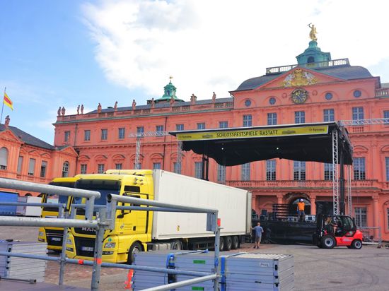 Zwei Trucks stehen vor einer Bühne, die im Hof des Rastatter Schlosses aufgebaut wird, Arbeiter sind am Werk. Die Bühne steht direkt vor der barocken Fassade der Barockresidenz.