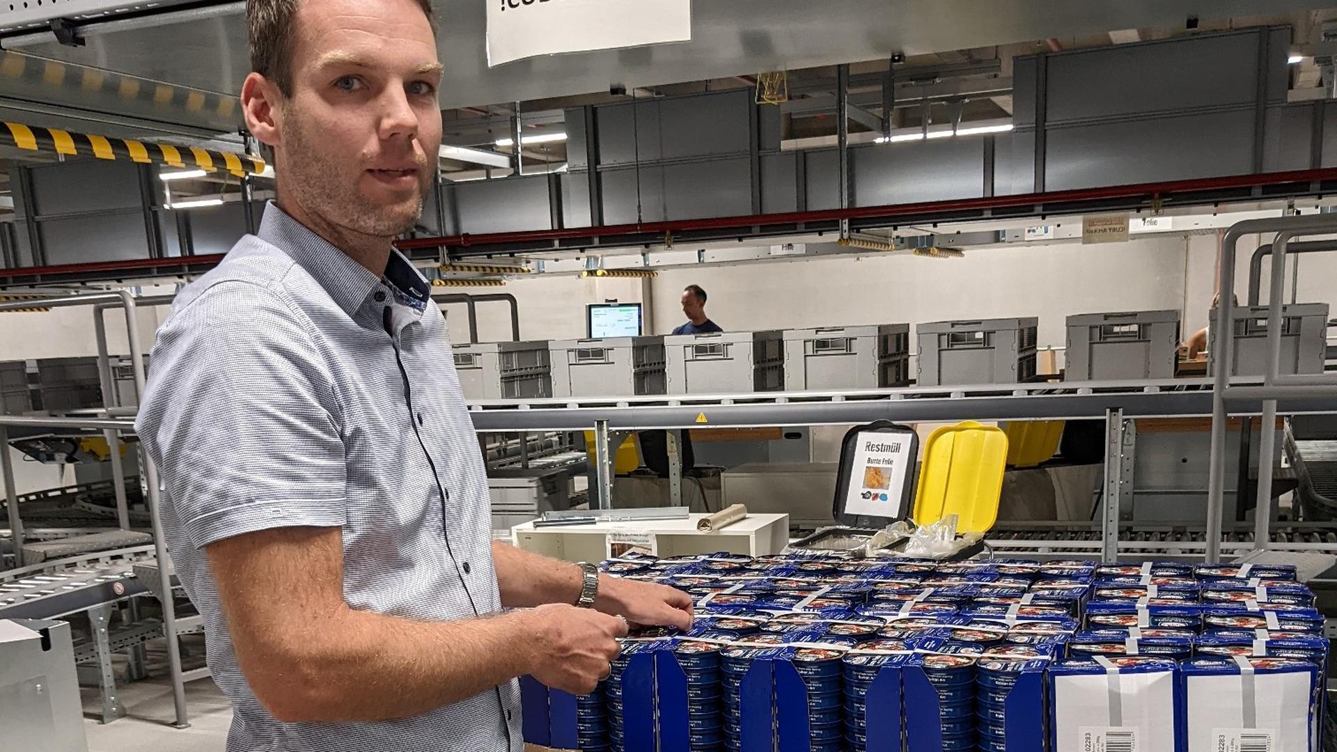 Betriebsleiter Björn Vahlenkamp erläutert die Umverpackung hunderter von Heringsfilet-Konserven.
 