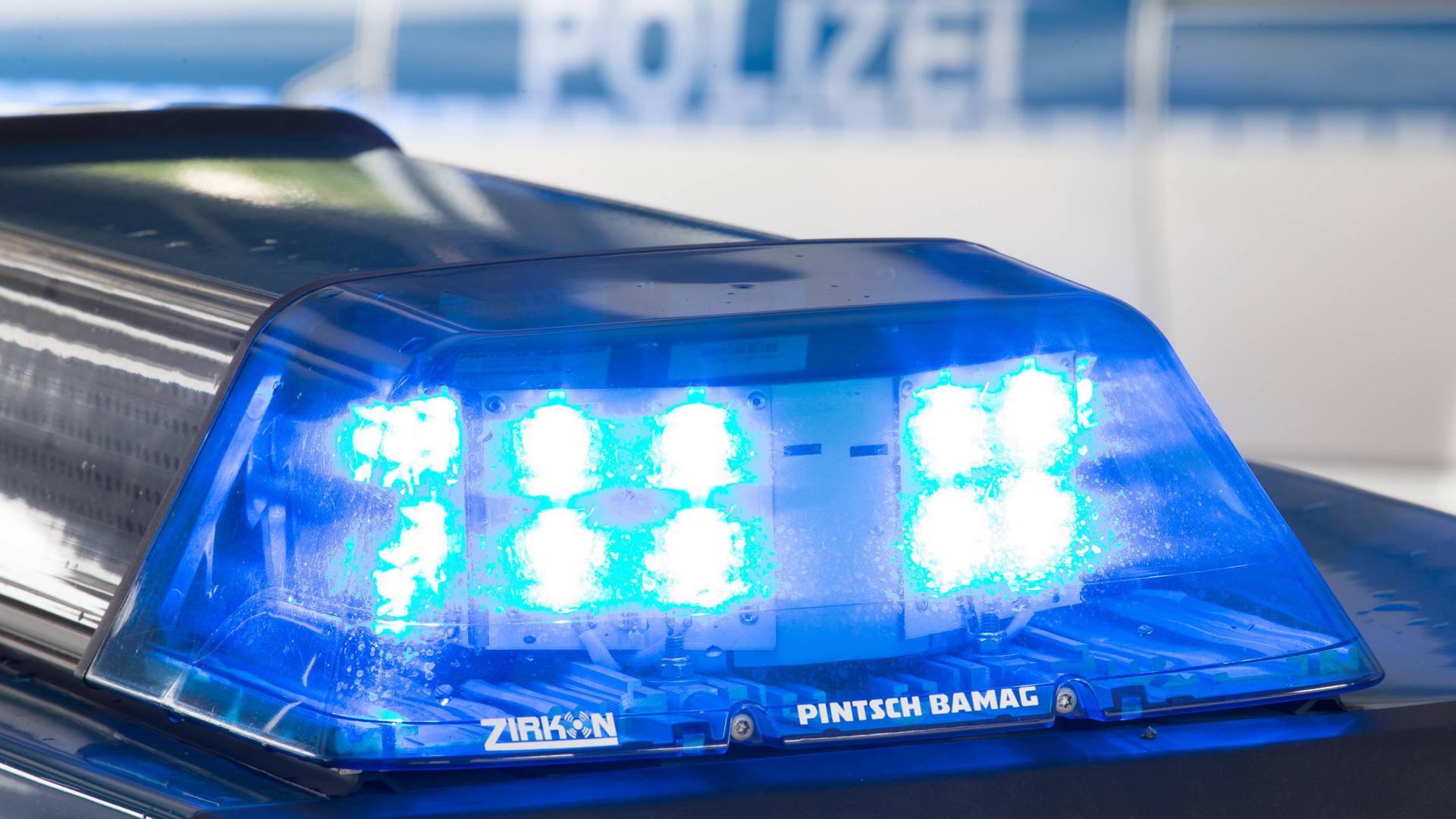 Ein Blaulicht leuchtet auf dem Dach eines Polizeiwagens. Im Hintergrund steht ein weiterer Streifenwagen.