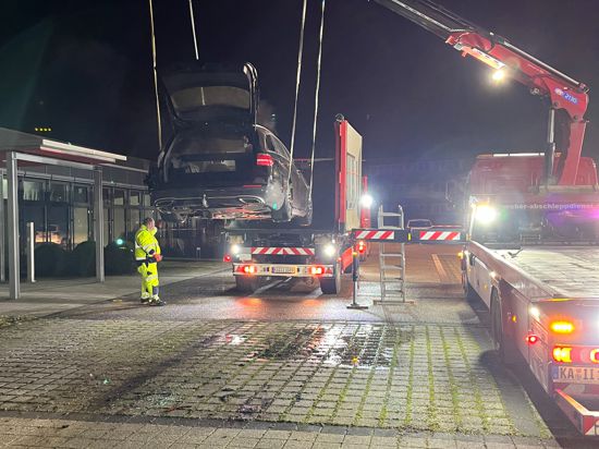 Vom Auto zum Gefahrgut: Der auf dem Parkplatz von Ruf Betten verbrannte Mercedes wird in einen Spezialcontainer gehievt.   