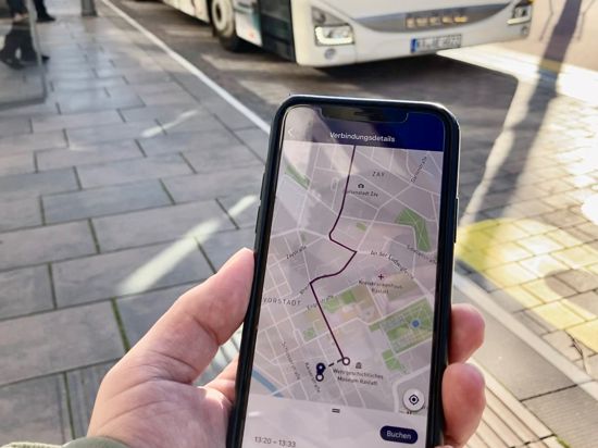 Smartphone wird vor einen Bus gehalten. 