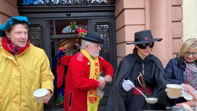 Rastatts OB Monika Müller (in Zorro-Verkleidung) und Beigeordneter Mats Tilebein (links) geben am Schmutzigen Donnerstag vor dem Rathaus Narrensuppe aus.