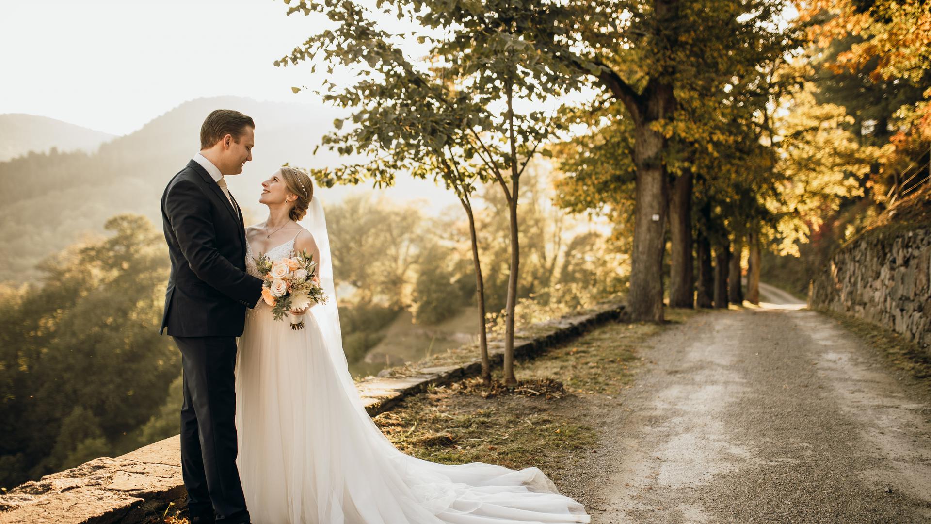 Ein Brautpaar vor Weinbergen im Herbst. 