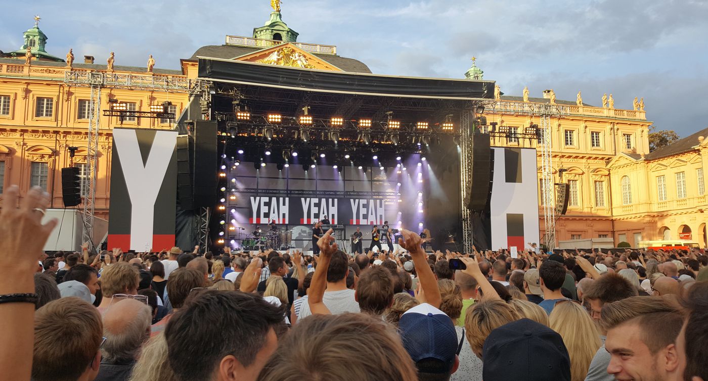 Open-air-Bühne vor der Kulisse des Rastatter Barockschlosses. Die Fantastischen Vier spielen, Fans jubeln ihnen zu. Das Konzert fand 2017 statt.
