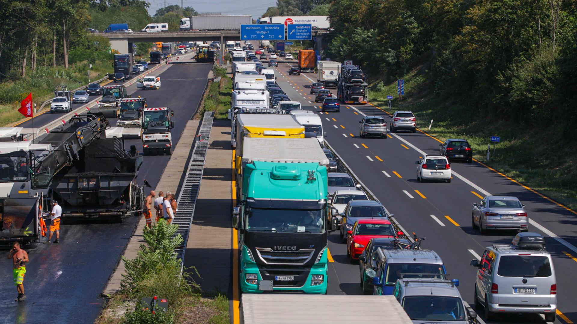Auf der Autobahn A5 bei Rastatt stehen hunderte Autos und Lkw im Stau, daneben läuft eine Straßen-Baustelle. 