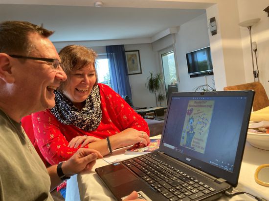  Jochen Fuchs und Andrea Herm schauen sich gemeinsam auf einem Laptop Werbematerial für den Fastnachtsumzug an