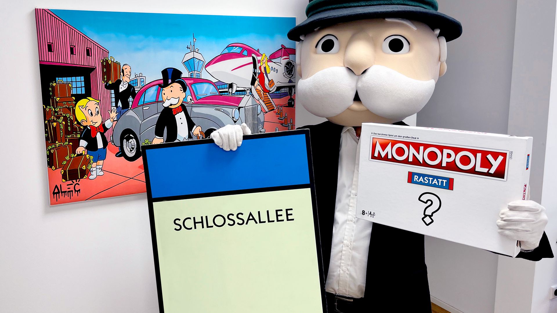Das Maskottchen Mister Monopoly hält einen Karton mit der Aufschrift Rastatt Monopoly in der Hand.