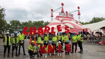 Mitarbeiter in Warnwesten und mit Helmen halten vor dem Zirkuszelt die Buchstabden CHARLES KNIE hoch.