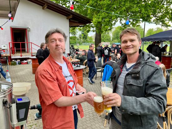 Zwei Männer stoßen mit Bier an.