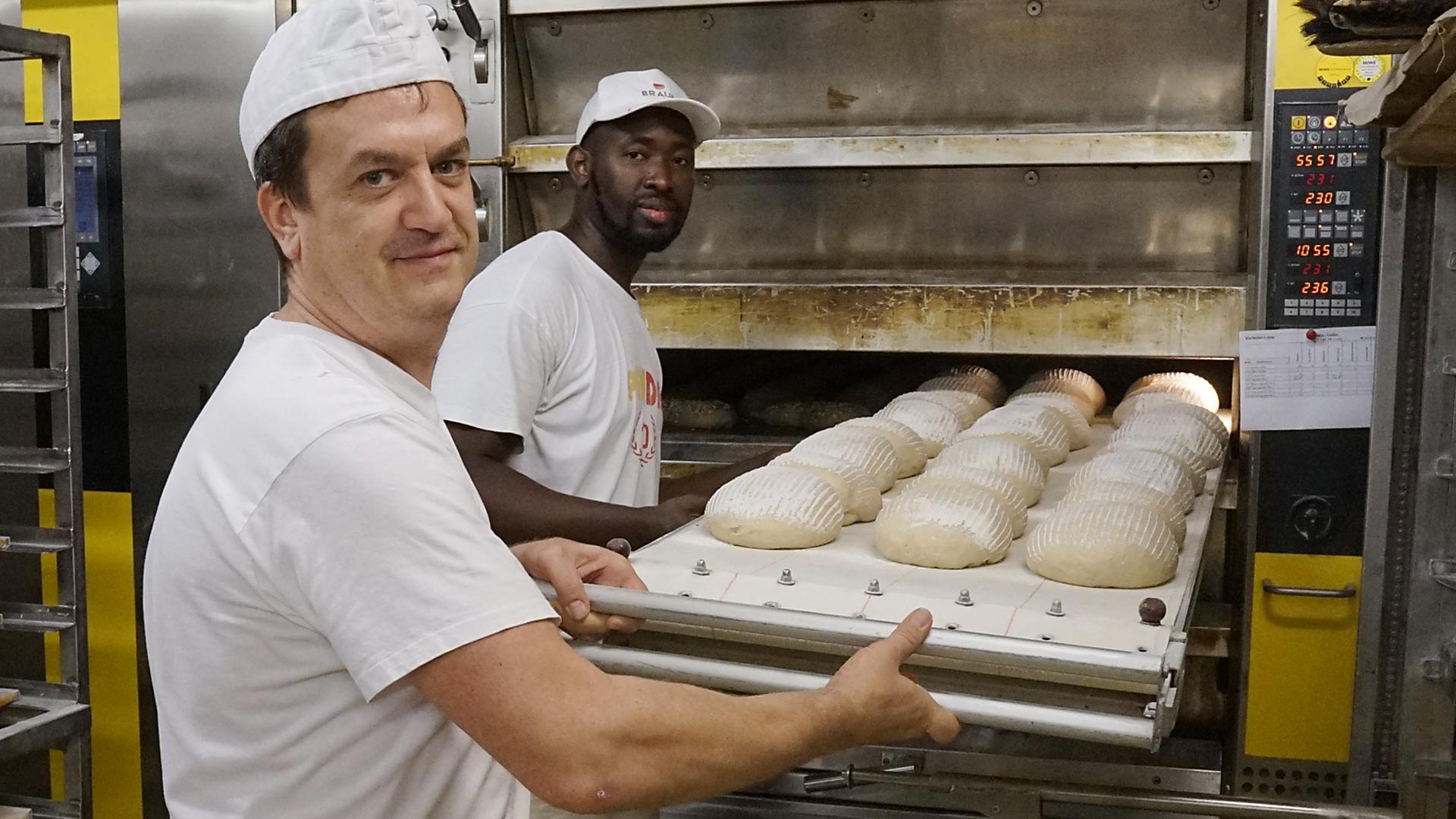 Bäckermeister Michael Schröder und sein Geselle Jank Drammeh in der Ötigheimer Backstube: letzte Handgriffe vor dem Einschießen der Brote in den Ofen.