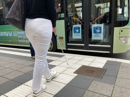 Eine Frau tastet sich mit ihrem Blindenstock an den Bus heran.