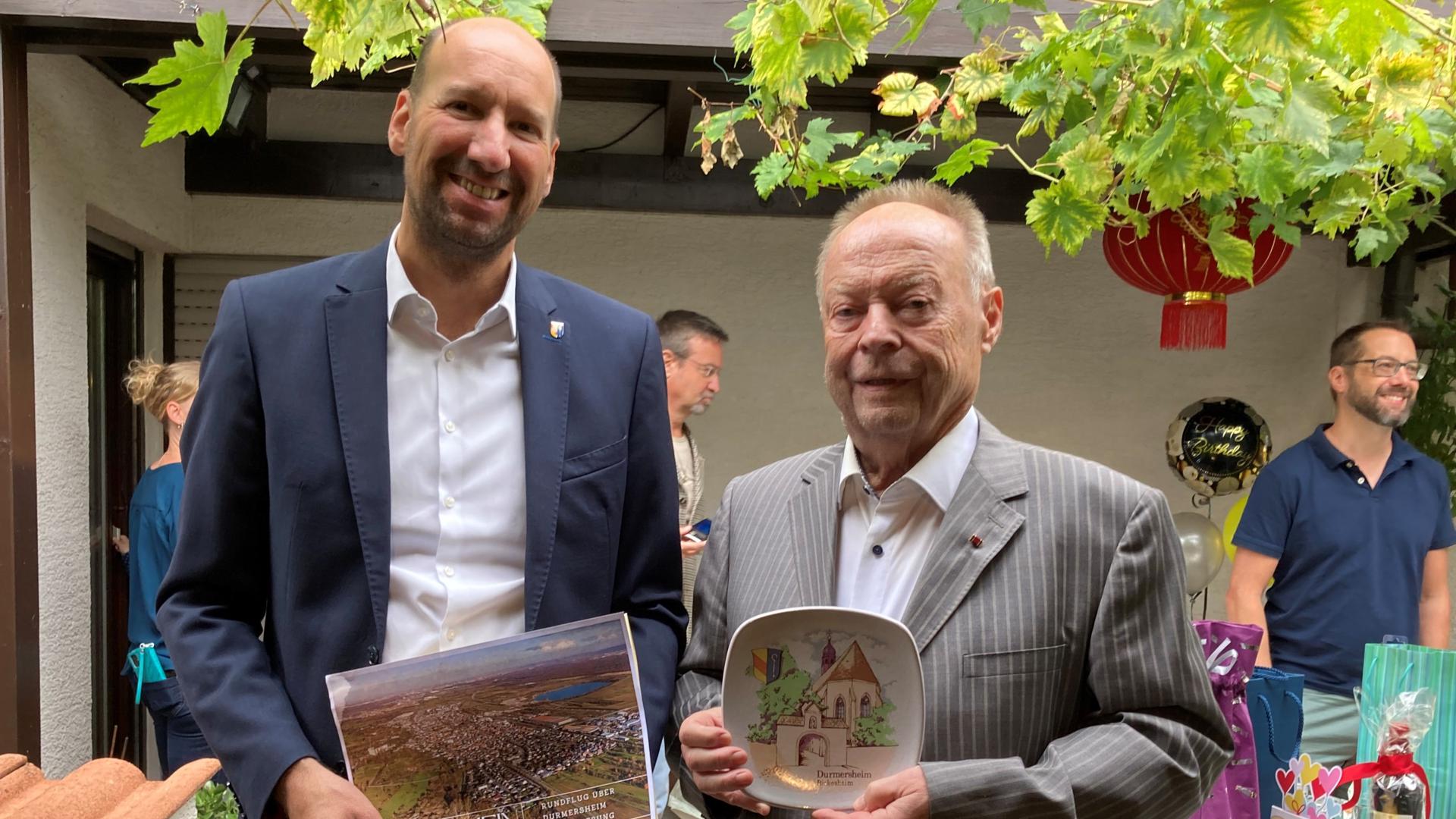 Bürgermeister Eckert und Ehrenbürger Kölmel mit Gutschein und Teller