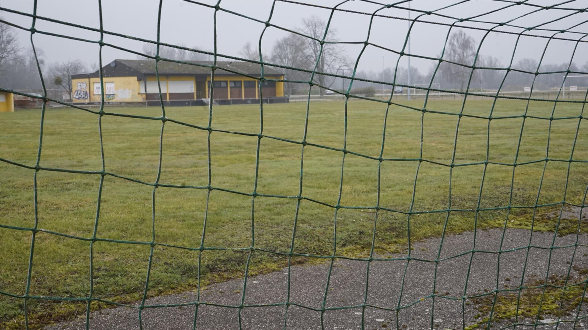 Fußballplatz fotografiert durch die Maschen eines Tornetzes         
