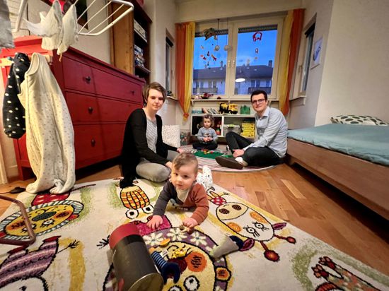 Eine Frau und ein Mann spielen mit zwei Kindern in einem Kinderzimmer auf dem Boden.