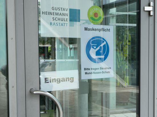 Das Bild zeigt den Eingang der Gustav-Heinemann-Schule. Ein Schild weist auf die bestehende Maskenpflicht hin.