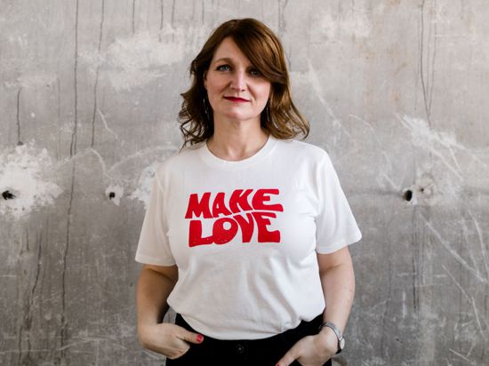 Die Buchautorin und Traumatherapeutin Annette Hosenfeld aus Landau steht vor einer grauen Betonwand. Sie trägt ein Shirt mit der Aufschrift „Make Love“.