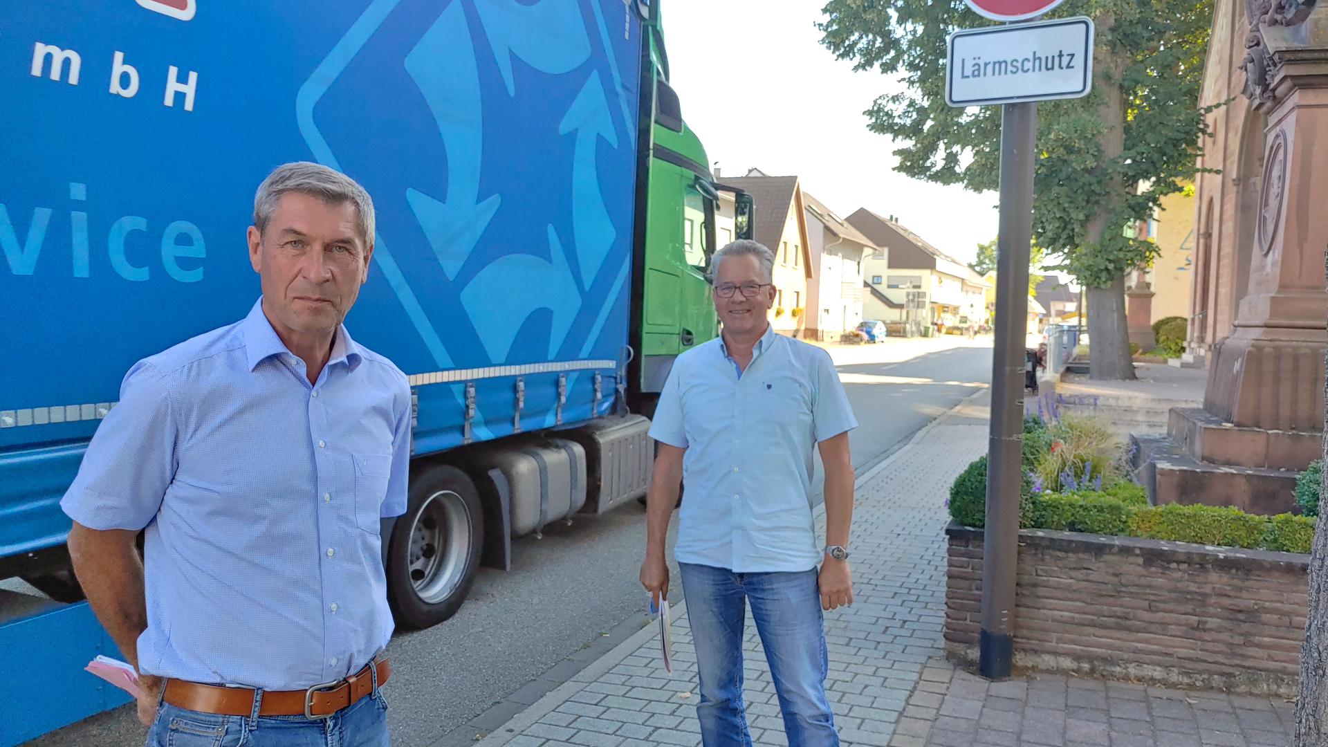 Wie eine Wand: Ein Lastwagen schiebt sich hinter Volker Lorenz und Michael Weber (von links) über die Hauptstraße. Das Tempolimit bringt wenigstens ein bisschen Erleichterung.
