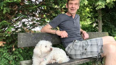 Ein Mann mit einem Hund auf einer Bank.