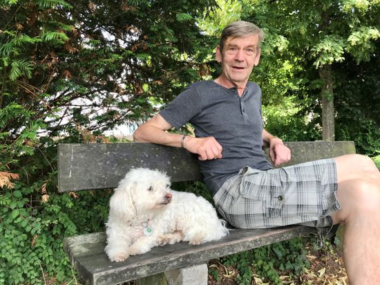 Ein Mann mit einem Hund auf einer Bank.