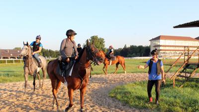 Bei der täglichen Morgenarbeit: Trainerin Carmen Bocskai (rechts) spricht bereits auf der Bahn mit den Reitern – zum Beispiel darüber, ob die Pferde mit Spaß gelaufen sind oder eher faul waren.