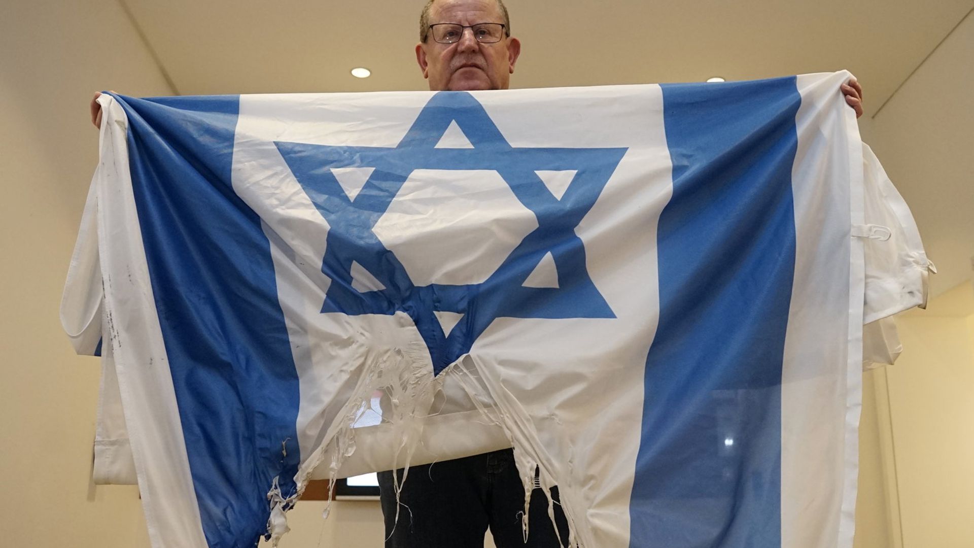 Ein Mann zeigt eine angebrannte israelische Flagge.