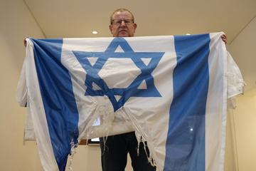 Ein Mann zeigt eine angebrannte israelische Flagge   