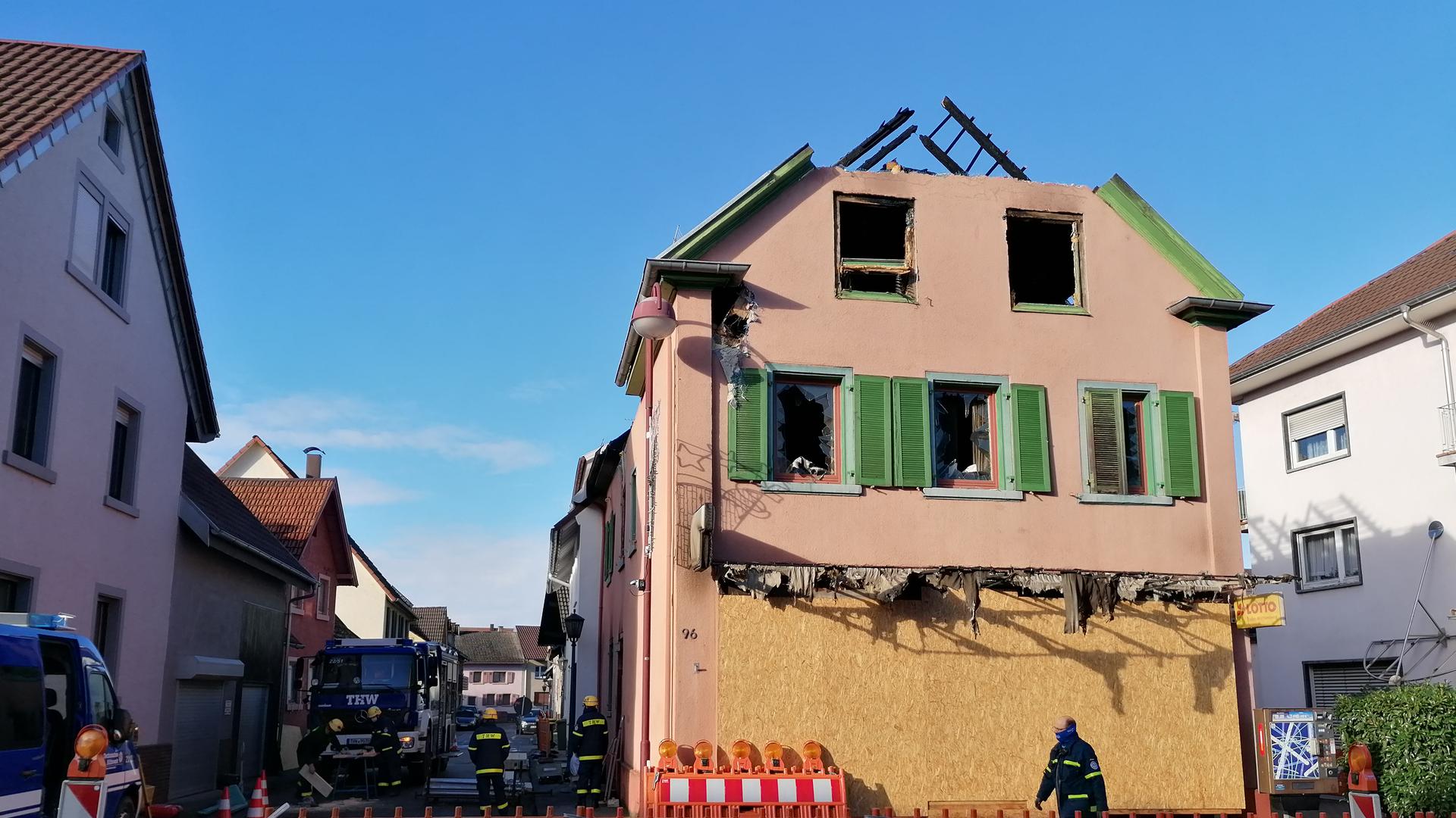 Ausgebranntes älteres Haus, Feuerwehr läuft drum herum