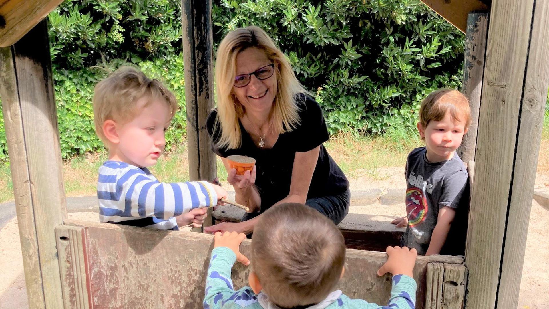Angelika Großmann, Gründerin des Eltern-Netzwerks Muggensturm, spielt mit drei Kindern in einem Spielhaus auf einem Spielplatz.