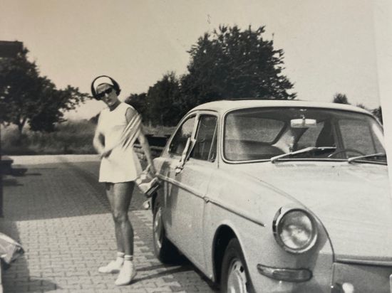 Eine junge Frau steht vor einem Auto trägt ein Tennisoutfit. Das Foto zeigt die Muggensturmerin Marlies Wolters in den Sechzigerjahren.