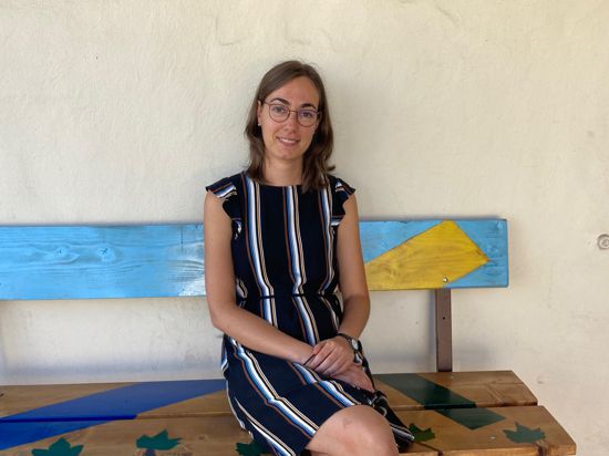 Christina Wächter, neue evangelische Pfarrerin, sitzt auf einer Bank vor der Muggensturmer Dreieinigkeitskirche.
