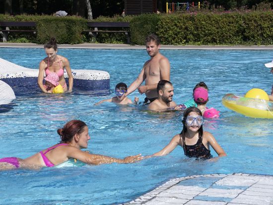 Kinder und Erwachsene planschen in einem Schwimmbecken             